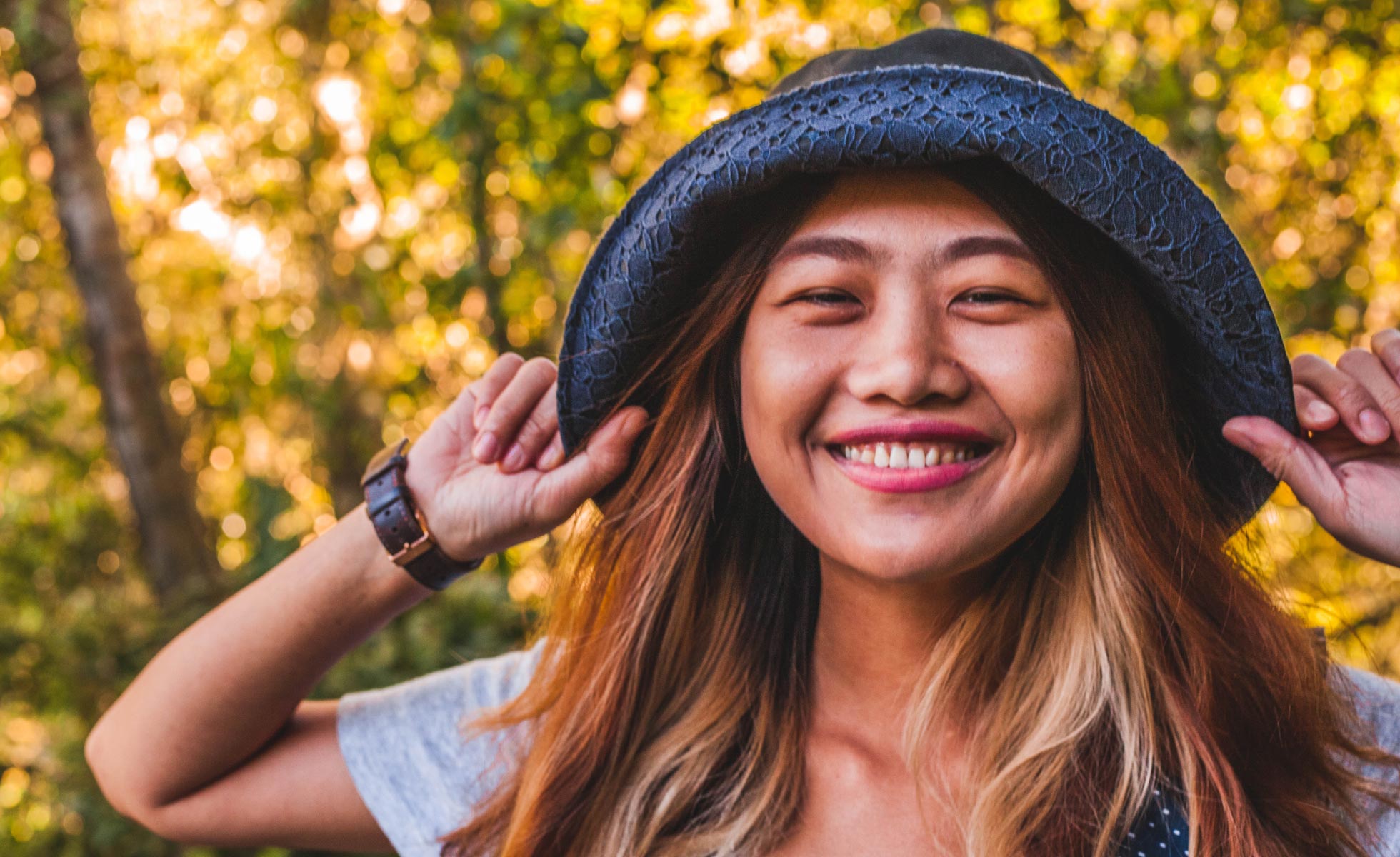 Young girl smiling and holding her hat